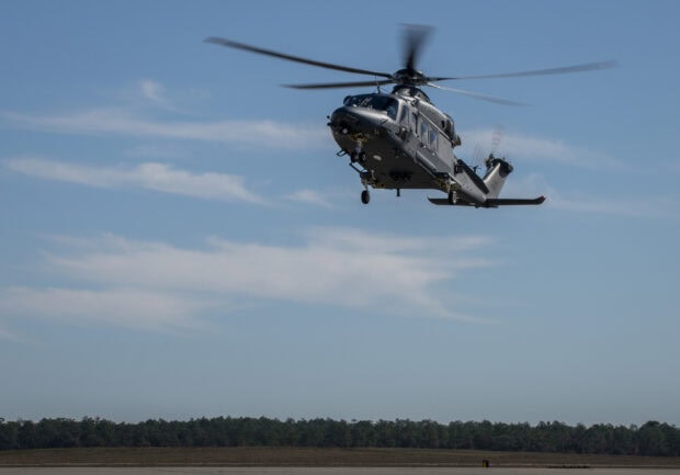 A military helicopter flying over the ground with clear blue sky in the background