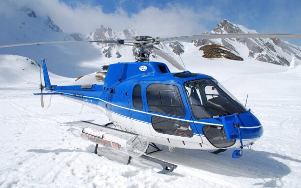 Blue helicopter on snowy mountain landscape in winter environment