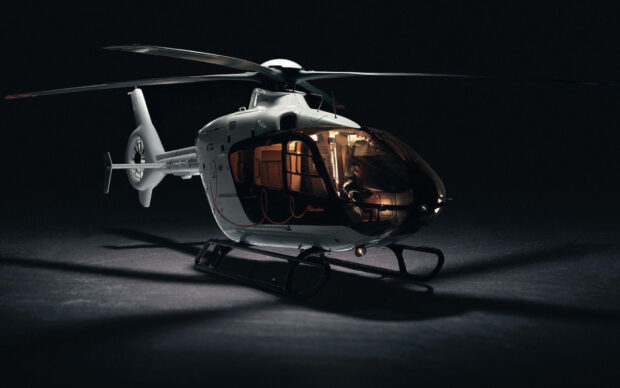 A white helicopter model illuminated in low light showing detailed cockpit and rotor blades