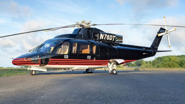 A black and red helicopter parked on a runway under a clear blue sky