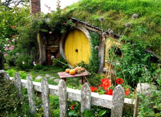 A charming garden in Hobbiton with a yellow round door surrounded by lush greenery and vibrant flowers