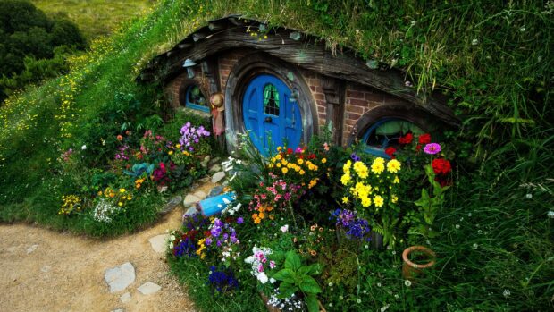 A charming hobbit hole surrounded by vibrant flowers and lush greenery in a peaceful garden setting