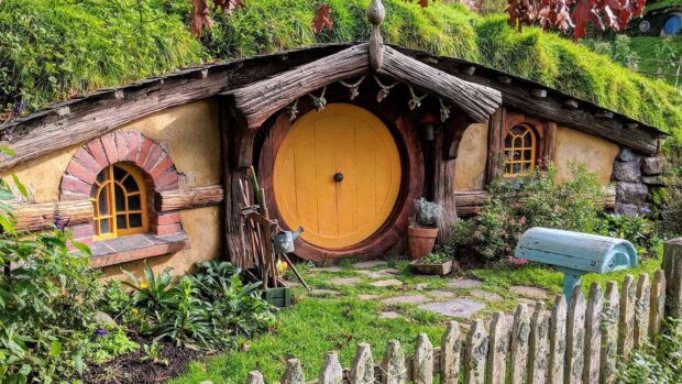 A charming hobbit hole with a yellow round door surrounded by greenery in Hobbiton