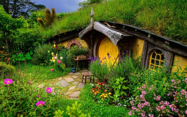 A charming Hobbiton home surrounded by lush greenery and colorful flowers in a peaceful garden setting