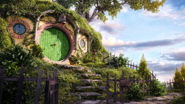 A cozy hobbit house with a round green door surrounded by lush greenery and stone steps