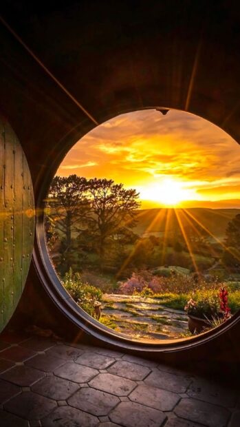 View of Hobbiton countryside with sunset seen through round door opening