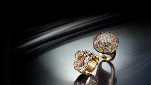 Two elegant gold rings with sparkling jewels arranged on a reflective surface