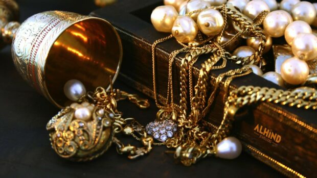 A collection of jewels featuring gold chains and pearls on a dark surface