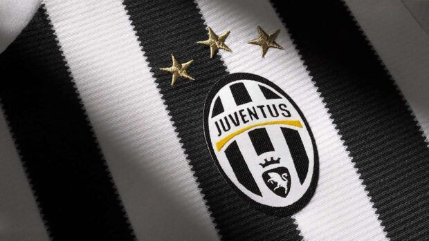 Close up of Juventus logo on a striped black and white jersey fabric with gold stars above