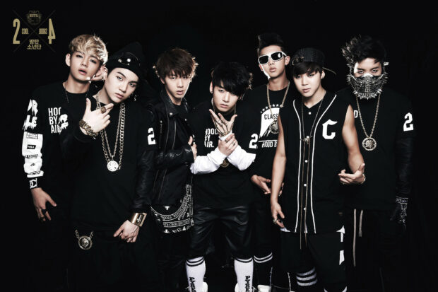 A popular K Pop band posing together in stylish black outfits and accessories