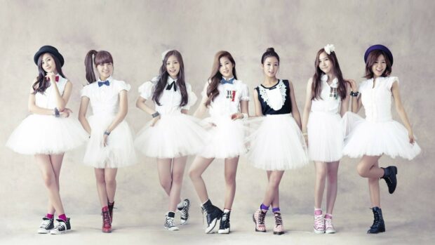 A popular K Pop group posing together in white dresses and colorful shoes showcasing K Pop style
