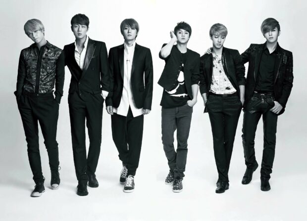 A fashionable K Pop group posing together in stylish black and white outfits