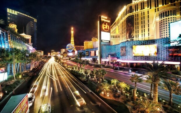 Night view of the Las Vegas Strip featuring palm trees and iconic buildings lit up at night