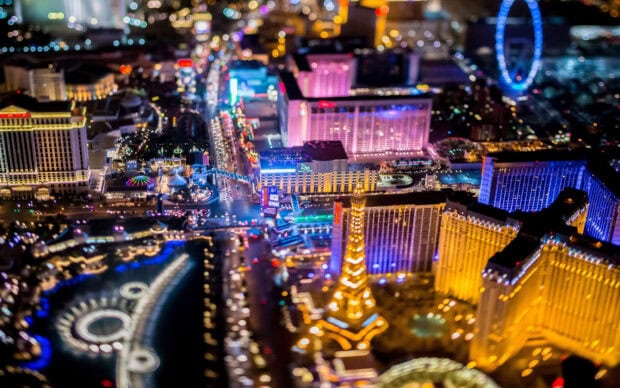 A vibrant nighttime view of the Las Vegas Strip featuring iconic casinos and the Eiffel Tower replica