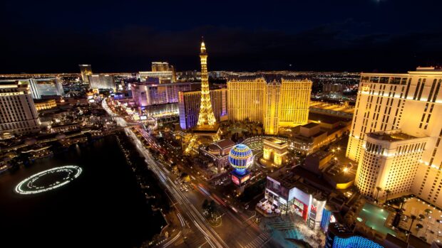 A vibrant Las Vegas Strip cityscape at night with illuminated landmarks and busy traffic