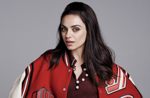 Mila Kunis wearing a red varsity jacket and pearl detailed shirt with long dark hair