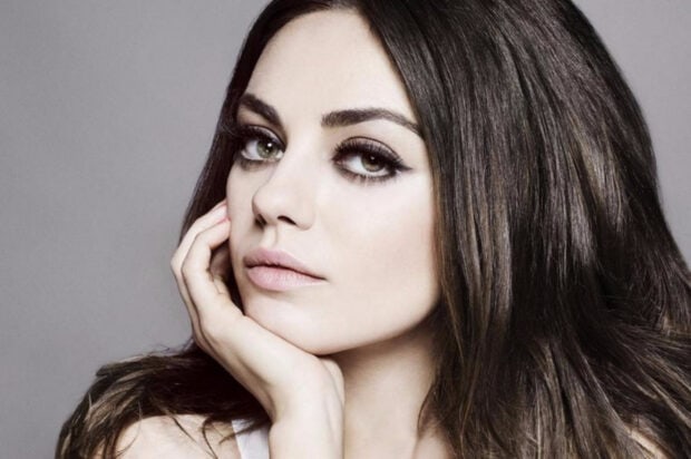 Close up of Mila Kunis with long dark hair resting her face on her hand