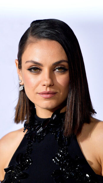 Mila Kunis wearing a black embellished dress with sleek hair and elegant makeup