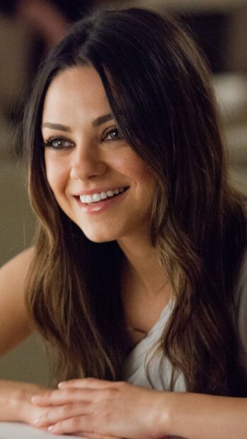 A close up of Mila Kunis smiling with long hair and natural makeup