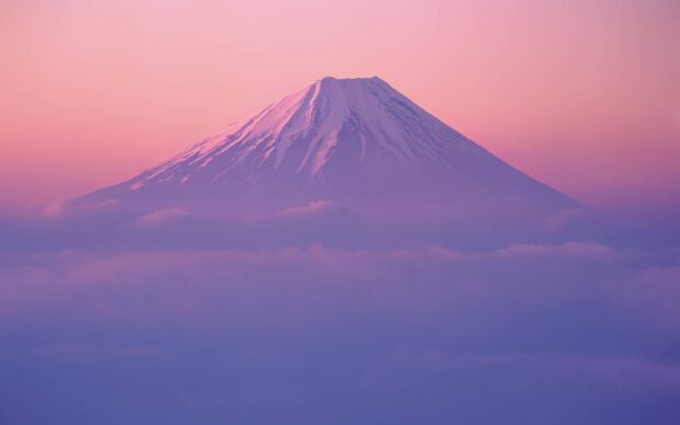 Snow capped Mount Fuji Japan surrounded by clouds at sunset light