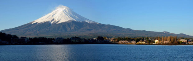 Snow capped Mount Fuji Japan towering over the town and lake at clear sunny day