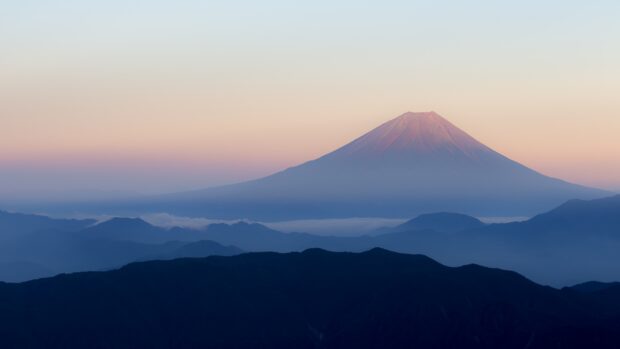 A serene view of Mount Fuji Japan during sunrise with mist over surrounding hills