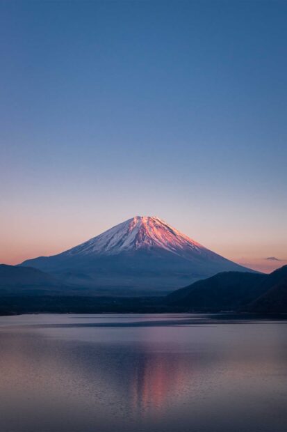 Snow capped Mount Fuji Japan during sunset reflecting on calm water