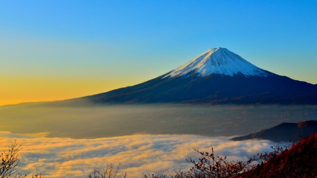 Snow capped Mount Fuji Japan with colorful sky at sunrise above clouds