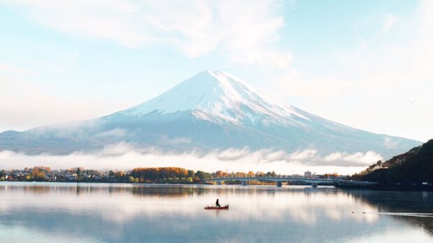 A serene view of Mount Fuji Japan with a person fishing on a calm lake