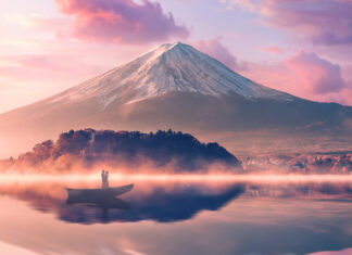 A serene view of Mount Fuji Japan with a couple in a boat on a misty lake at sunrise