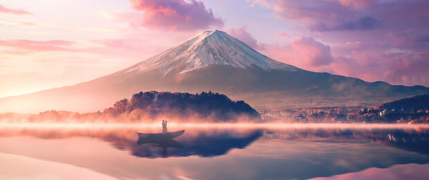 A serene view of Mount Fuji Japan with a couple in a boat on a misty lake at sunrise