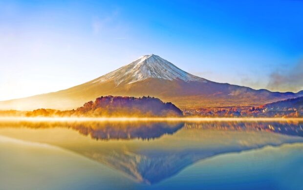 Snow capped Mount Fuji Japan reflected on calm lake at sunrise