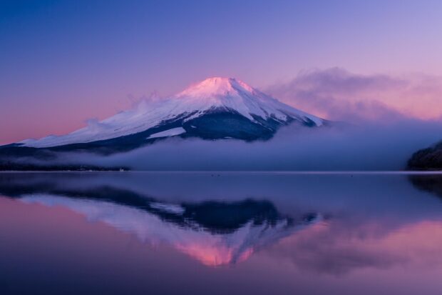 Snow capped Mount Fuji Japan reflected in calm lake at sunrise