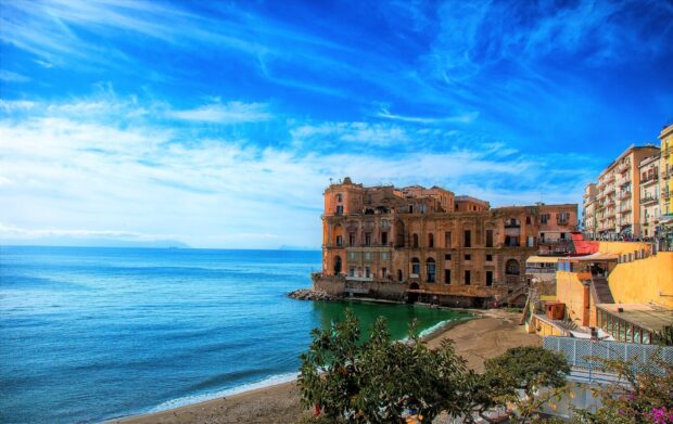 Historic Naples cityscape with coastline under blue sky and calm sea