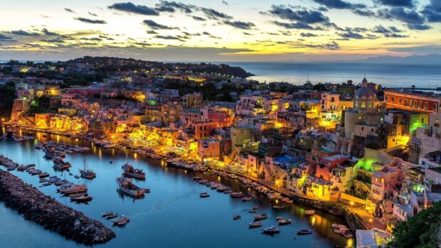 Night view of Naples cityscape by the sea with boats and illuminated buildings