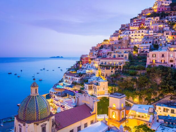 A panoramic view of Naples coastal town with colorful buildings and sea boats at dusk
