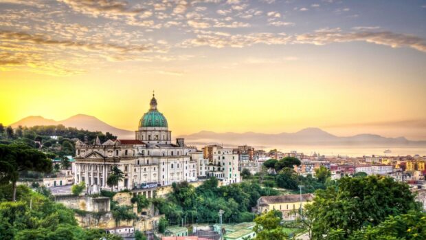 A scenic cityscape of Naples with historical architecture and lush greenery at sunrise