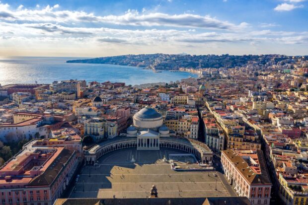 Aerial view of Naples cityscape with historical buildings and coastline under blue sky