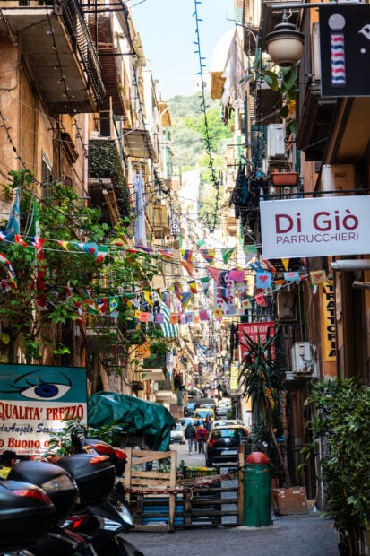 Narrow street with colorful flags and buildings in Naples cityscape