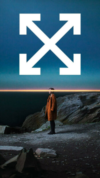 A person in an orange coat standing on rocky ground with Off White arrows symbol above their head