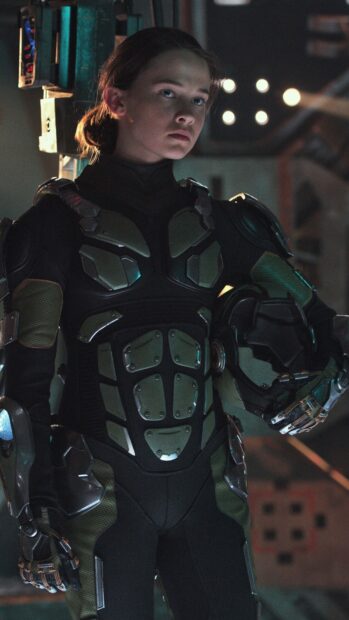 Young pilot wearing futuristic suit from Pacific Rim standing confidently in dimly lit room