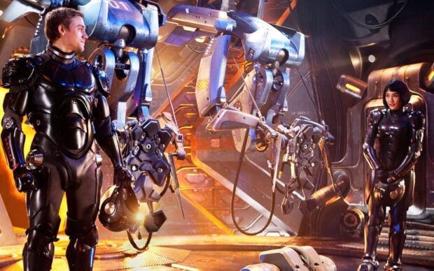 Two Pacific Rim pilots preparing in high tech suits inside a mechanical control room