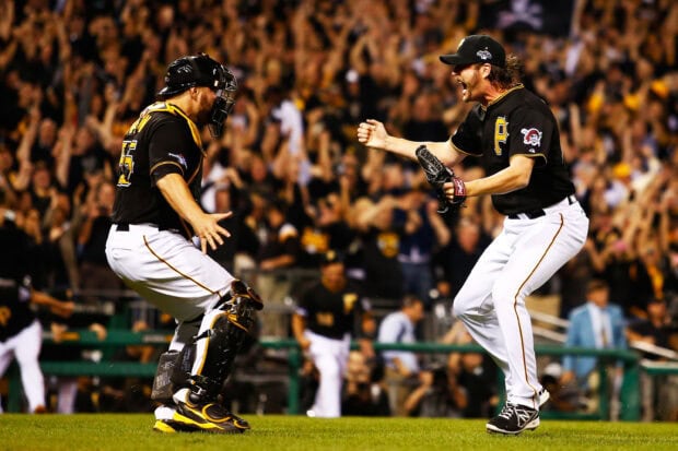 Two Pittsburgh Pirates players celebrating a game moment on the field with a cheering crowd in the background