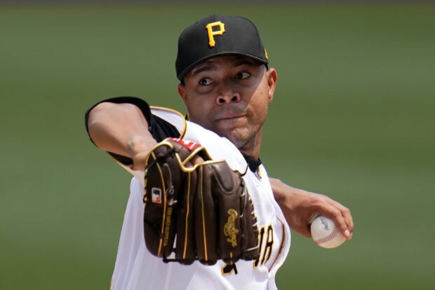 A Pittsburgh Pirates player pitching a baseball during a game in a white uniform with a black cap