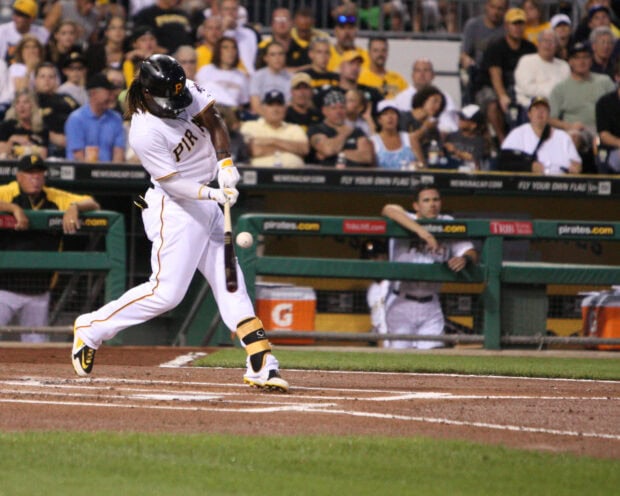 A Pittsburgh Pirates player swinging a bat during a baseball game in front of a crowd