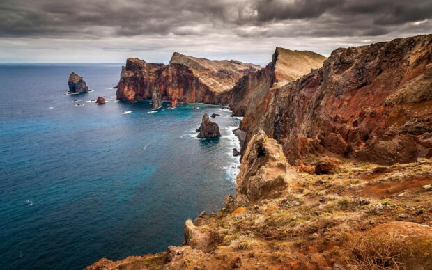 Rugged coastline landscape in Portugal with rocky cliffs and ocean view under cloudy sky
