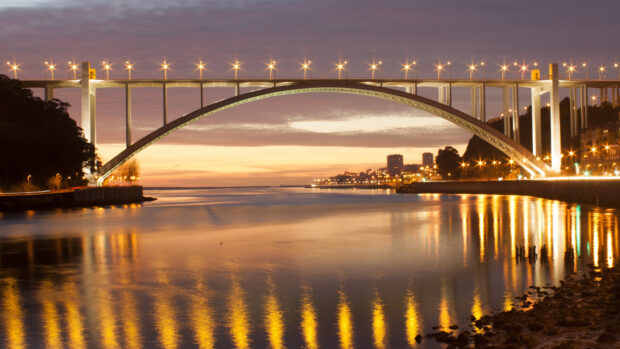 The river at sunset with the famous bridge in Portugal reflecting golden lights on the water