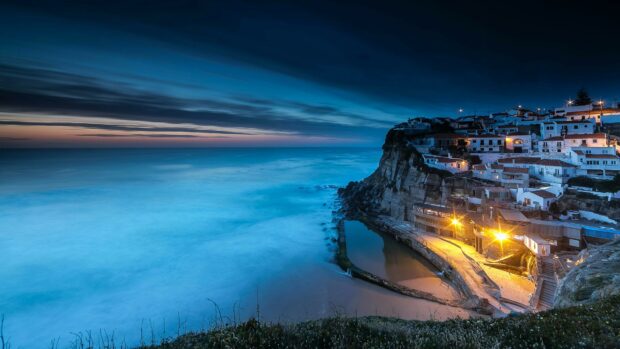 Coastal village in Portugal glowing at dusk with ocean waves and cliffs visible