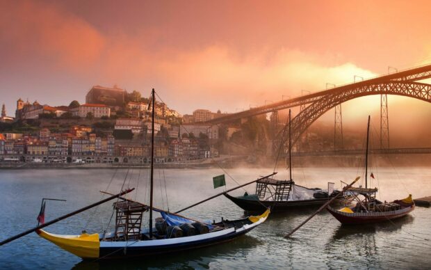 Traditional Portugal boats on the river with the iconic Porto cityscape in the background