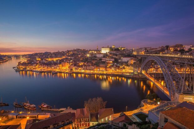 Evening cityscape of Porto Portugal with river and bridge illuminated at twilight
